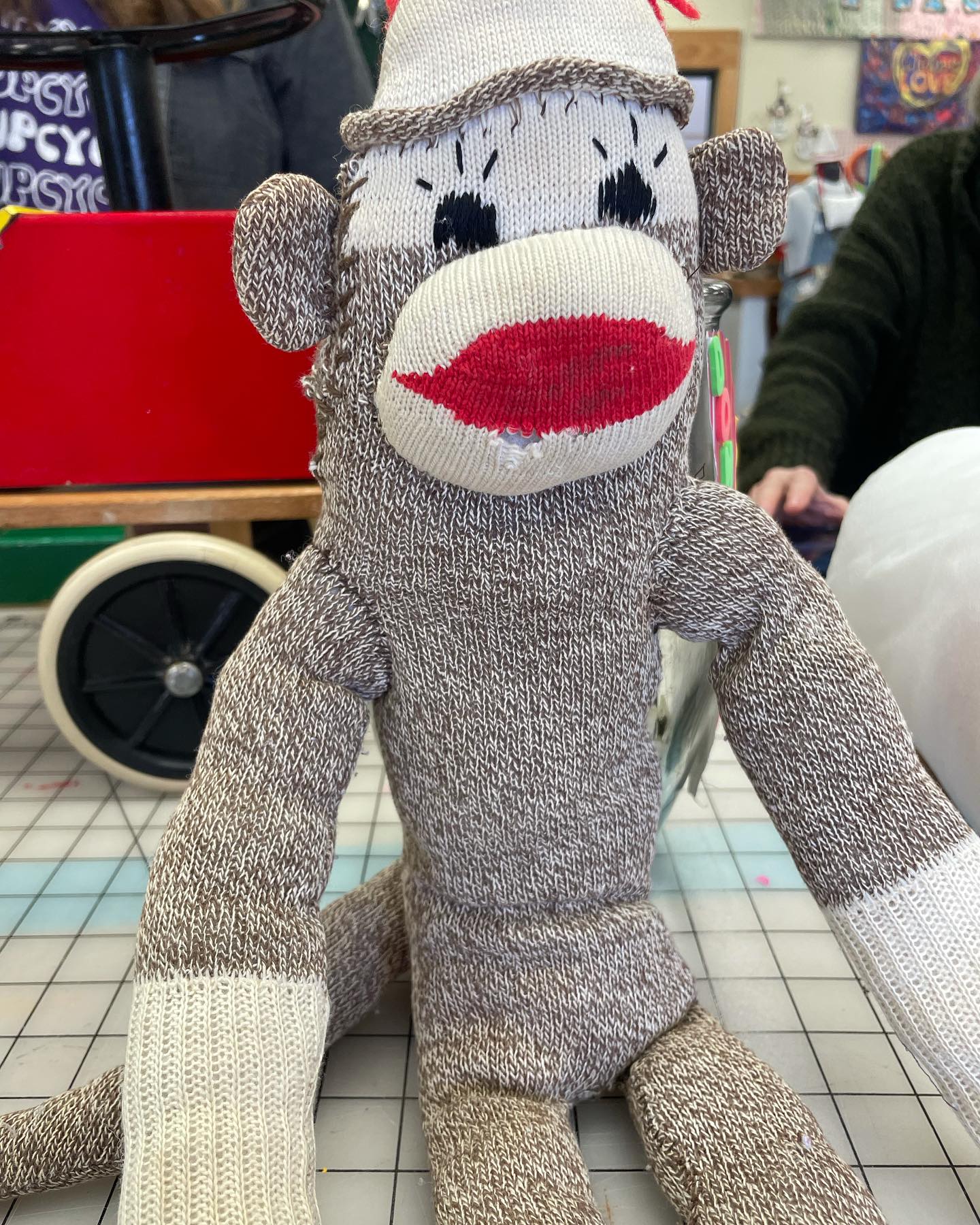 A sock monkey sitting on a table at the community makerspace, where patrons can bring items for repair or mending.